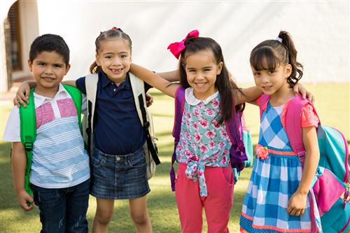 Three girls, one boy wearing backpacks ready for school 